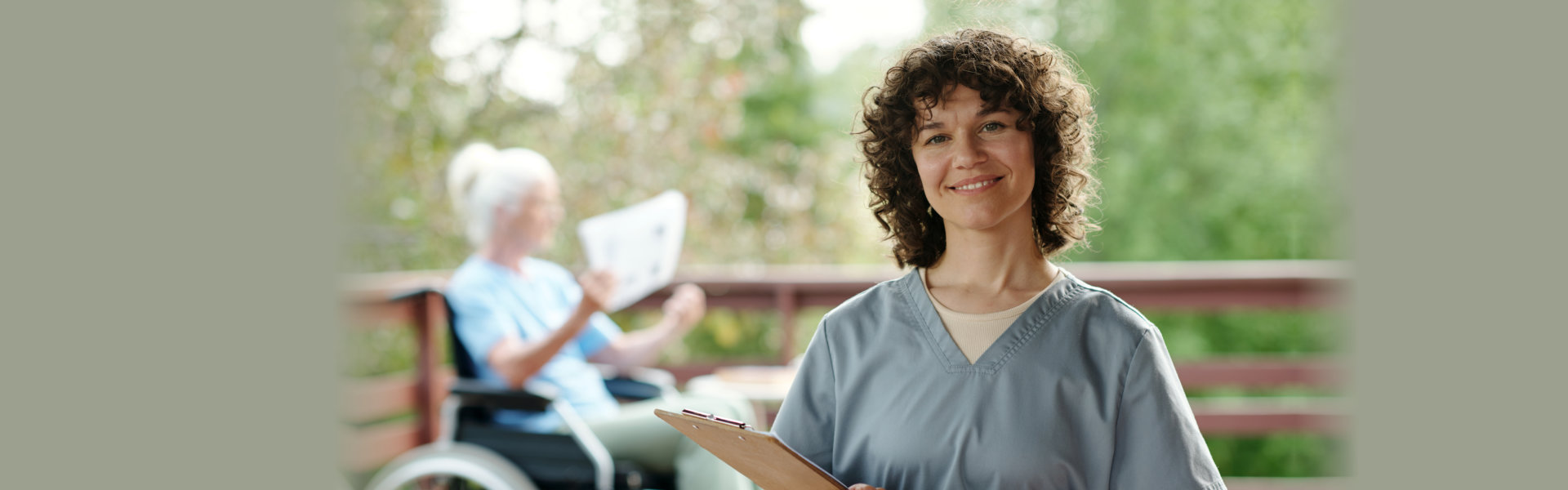Happy young nurse or caregiver with clipboard looking at camera