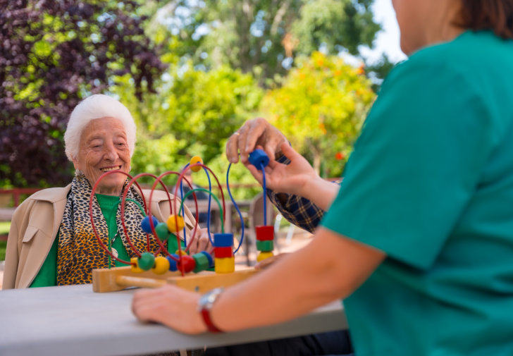an elder and a caretaker playing with abacus